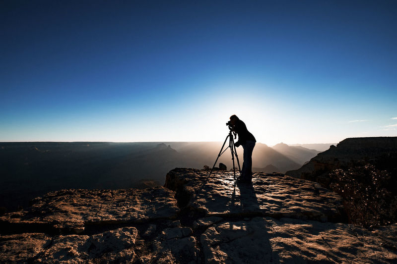 Silhouette man photographing through camera while standing on mountain