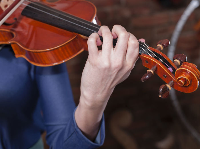 Cropped image of woman playing violin at home