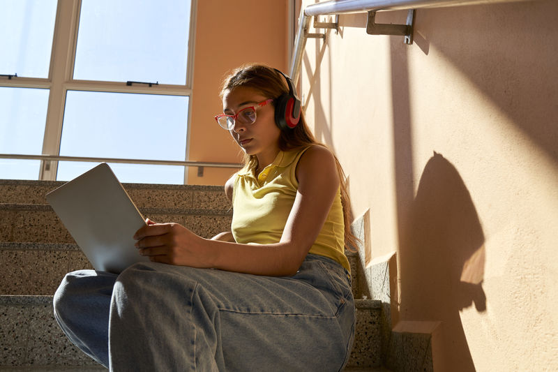 Young female student working with her computer sitting inside buildings