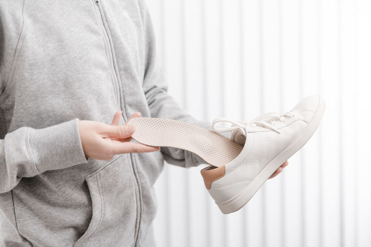 Midsection of woman inserting insole in shoe