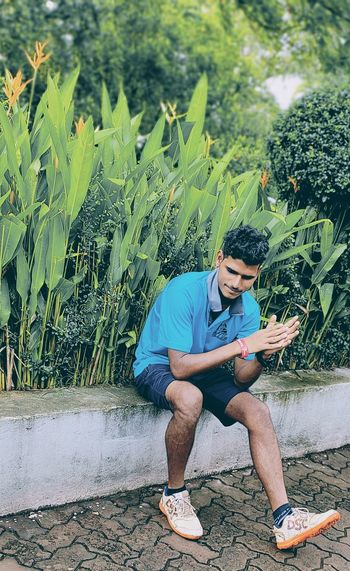 Young man using mobile phone while sitting outdoors