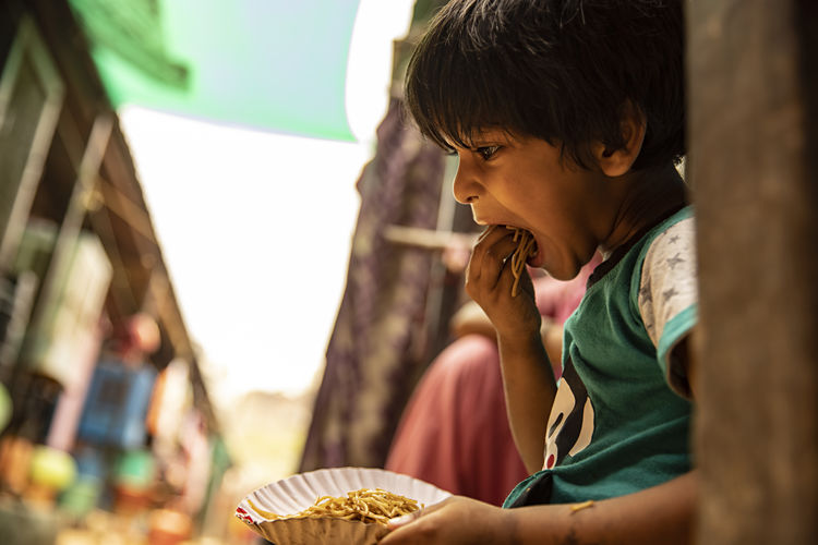 Closeup of a slum boy eating noodles