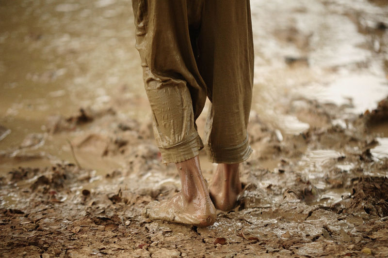 Low section of man walking on mud