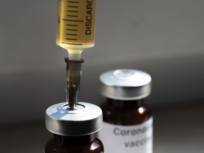 Close-up of syringe over bottle
