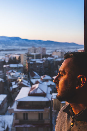 Portrait of young man in city against sky