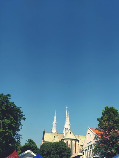 Church by building against clear blue sky