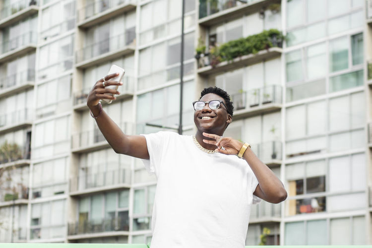 Happy man gesturing and taking selfie through mobile phone