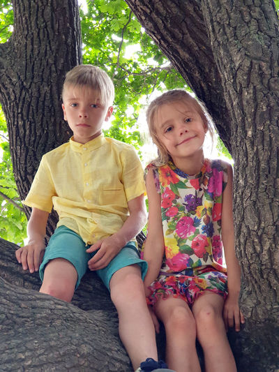 Siblings sitting on tree trunk