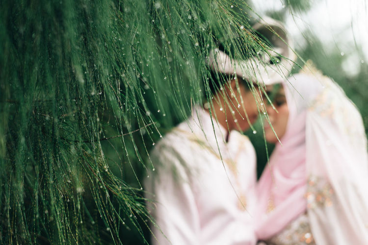 Couple in wedding dress standing by plants