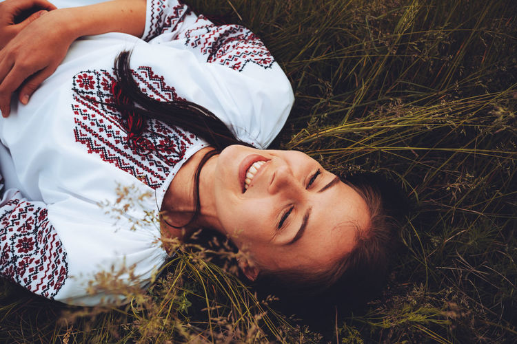 Photo of a smiling young woman in ethnic ukrainian shirt, enjoying the beautiful weekend getaway