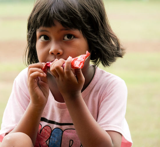 Portrait of young woman eating food at park