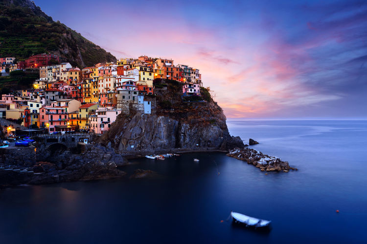 Aerial view of townscape by sea against sky during sunset