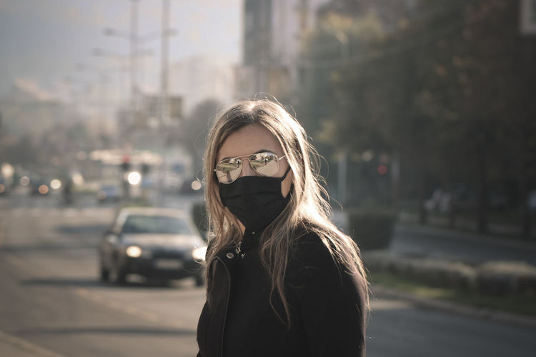 Portrait of young woman standing on street in city