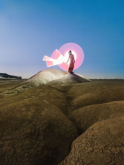 Full length of woman standing on pink land against sky