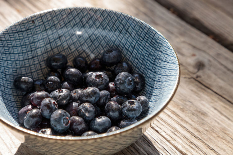 Organic blueberries in a blue and white bowl on the rustic wood background of an old farm table 
