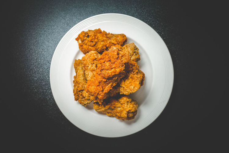 High angle view of chicken wings in plate over black background