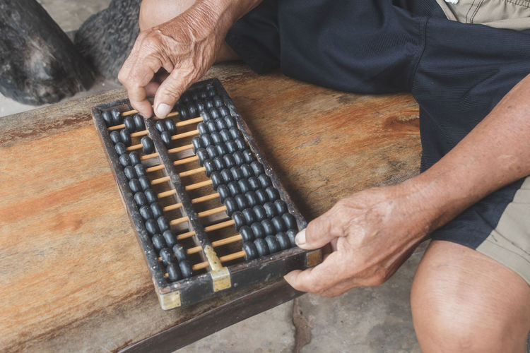 Midsection of man playing with abacus