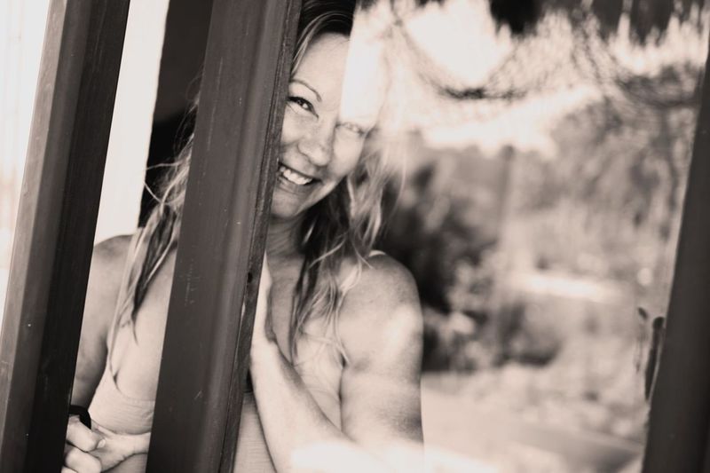 Portrait of smiling happy woman seen through glass door