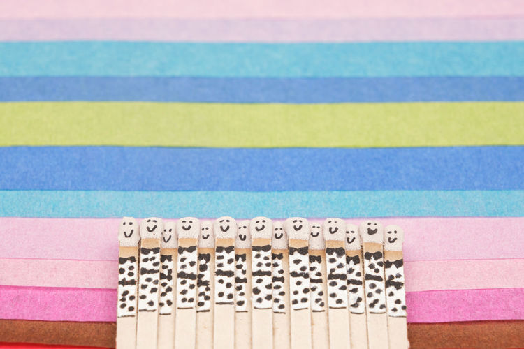 Matchsticks with faces painted on the heads on multicolored paper