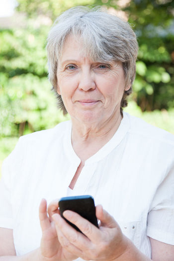 Portrait of senior woman using phone at park