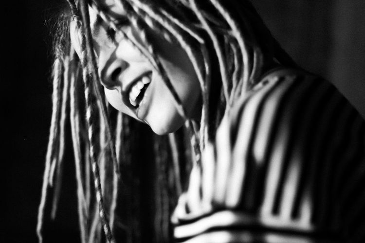 Close-up of cheerful woman with dreadlocks in darkroom