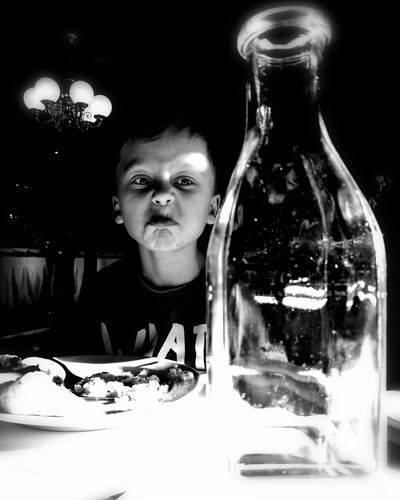 Portrait of man with bottle on table against black background