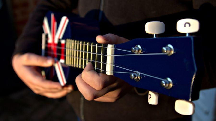 Hands playing a red, white and blue ukelele