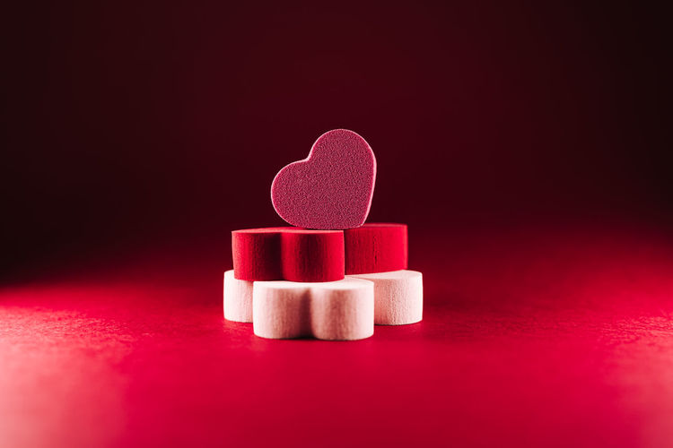 Close-up of heart shape on pink table against colored background