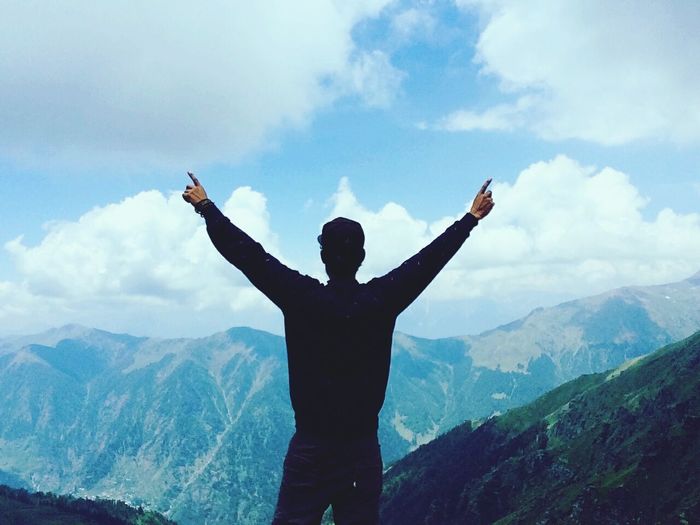 Rear view of man standing with arms outstretched against himalaya mountain
