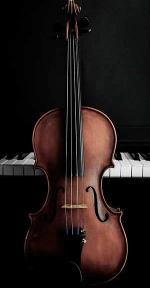 Close-up of violin and piano against black background