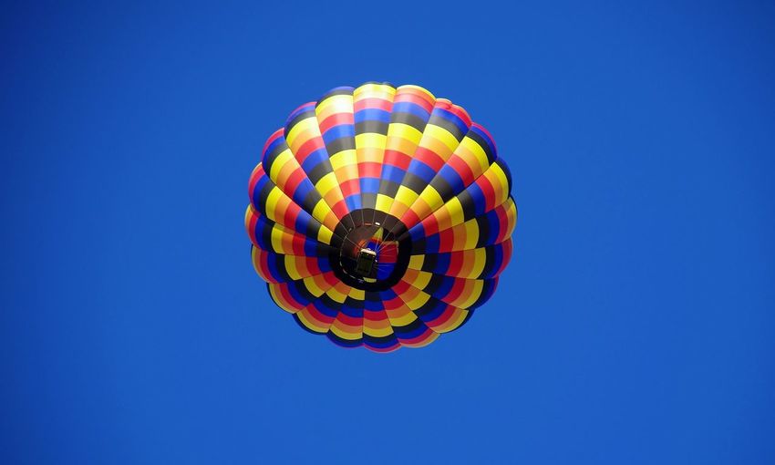 Low angle view of multi colored balloons against clear blue sky
