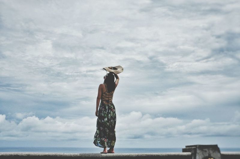 Rear view of woman standing against cloudy sky