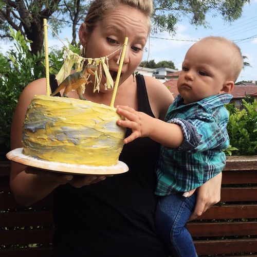 Woman holding cake and baby boy in back yard