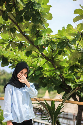Portrait of woman standing against plants and trees 