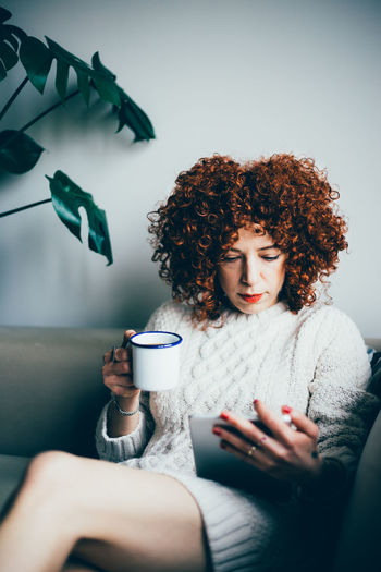 Woman having coffee while using digital tablet