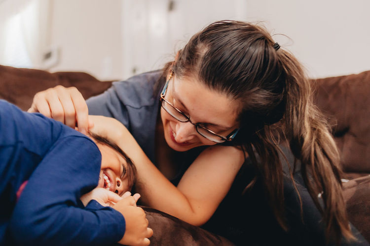 Smiling mother playing with daughter sitting at home