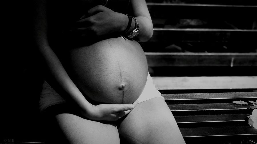 Midsection of pregnant woman sitting on bench
