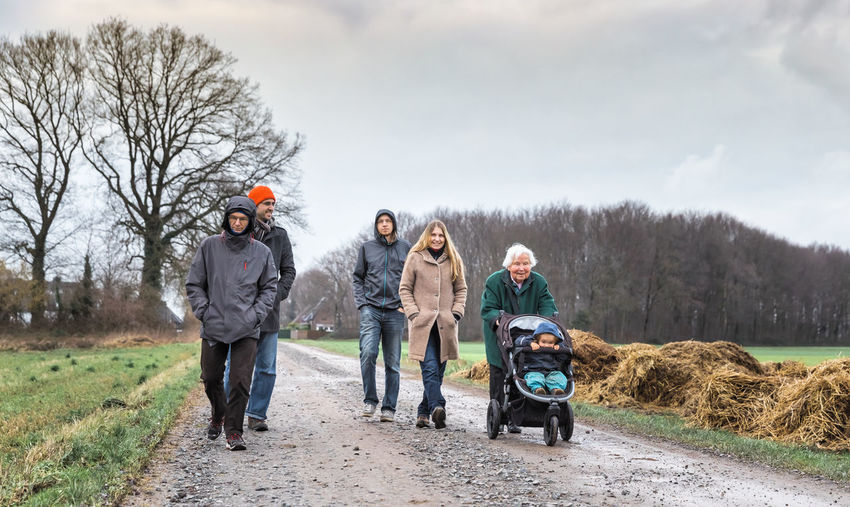 Full length of family walking on road against sky