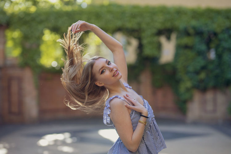 Portrait of smiling young woman tossing hair in park