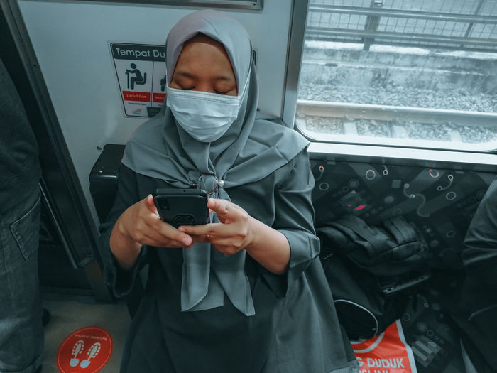 Woman using mobile phone while sitting in train