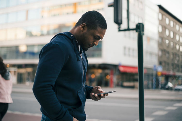 Side view of man using smart phone on street