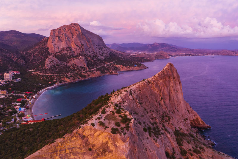 Pink sunset in novyi svit in autumn with mount falcon in background. sudak, crimea. aerial view