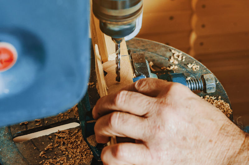 Drilling holes in wooden board. making wooden legs for easels. joinery work. hands of master