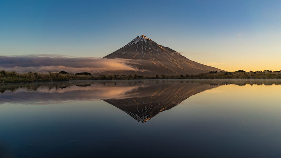 Scenic view of lake by mountains against clear sky