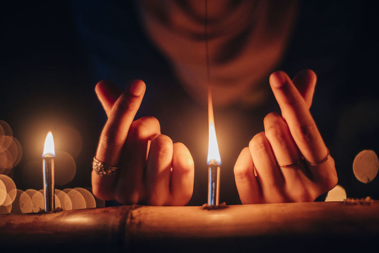Close-up of hand around lit candles