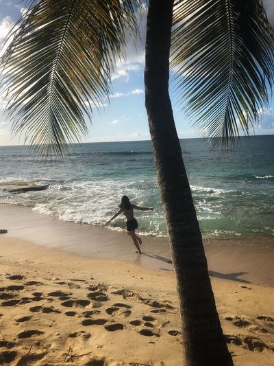 Rear view of woman with arms outstretched running at beach