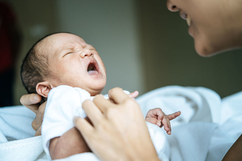 Midsection of mother holding baby at home