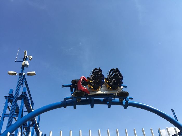 Low angle view of amusement park ride against blue sky