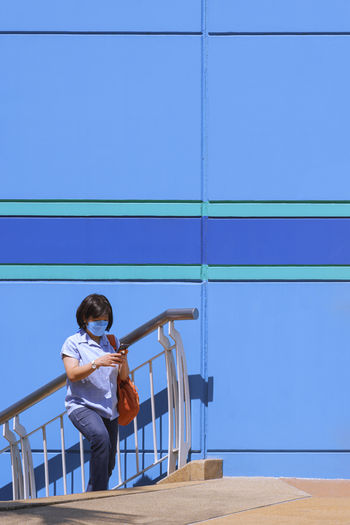 Full length of girl on railing against blue wall
