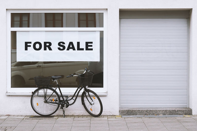 For sale sign in store window with bicycle parked outside - shop vacancy due to business closure 